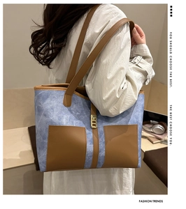 Detail of blue canvas and brown leather tote bag showing golden lock and front pockets
