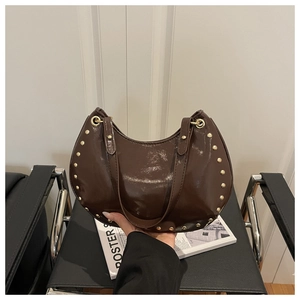 Détail du sac bandoulière en cuir verni marron foncé avec rivets punk dorés brillants