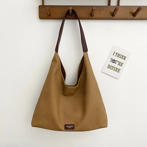 Minimalist ginger yellow canvas tote bag with brown leather strap hanging on a wall