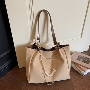 Elegant beige tote bag with pearl chain and brown straps on a minimal wooden floor