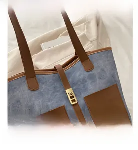 Detail of denim and brown leather patchwork tote bag with gold metal buckle closure