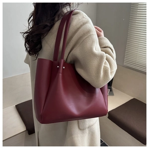 Close-up of deep burgundy leather tote bag styled on model in minimalist office setting