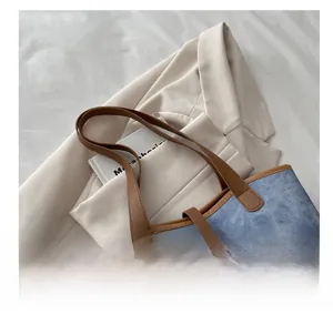 Detailed view of blue denim and brown leather texture on a stylish tote bag