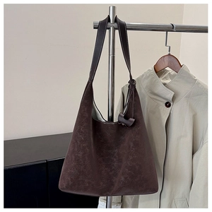 Dettaglio della borsa tote in pelle scamosciata marrone scuro con texture opaca e fibbie