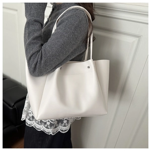 Detail view of the white minimalist tote bag showing soft matte texture and silver rivets