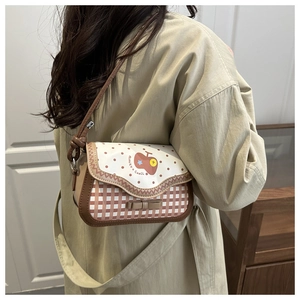 Detail of checkered crossbody bag with red polka dots and apple print on a model