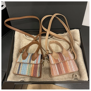 Detail of woven mini crossbody bags with contrast wave patterns in a gift box display