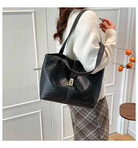 Close-up of black woven texture tote bag with elegant gold metal twist lock buckle detail