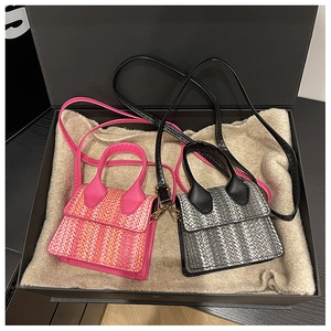 Detailed view of mini tweed woven handbags in pink and black on gift box padding