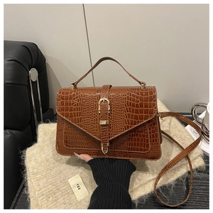 Close-up of caramel brown crocodile embossed faux leather handbag with gold metal clasp