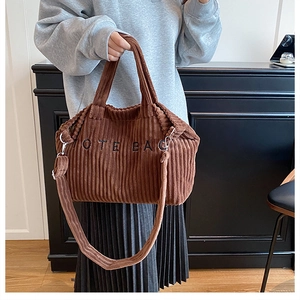 Close-up of brown corduroy tote bag featuring adjustable strap and TOTE BAG embroidery