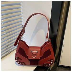 Detail of dark red crescent shoulder bag featuring metal studs and mixed leather texture