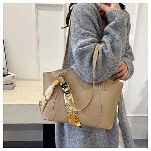Close-up of khaki leather tote bag with elegant silk scarf wrap and shoulder strap