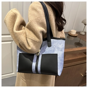 Blue denim tote bag with black leather pockets and gold hardware shown on model