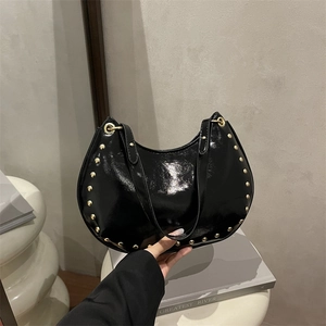 Sac hobo noir en cuir verni avec des clous dorés et des œillets métalliques