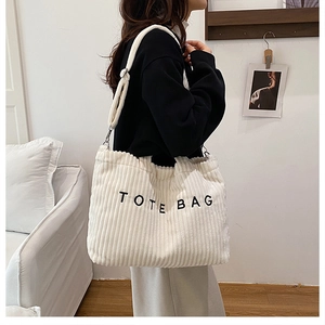 Detail of beige corduroy tote bag with black embroidery and adjustable strap