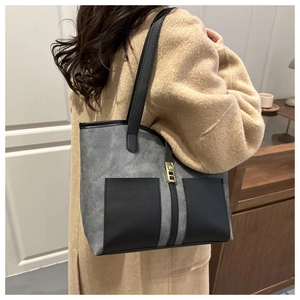 Detail of color-block tote bag with grey suede texture and black leather shoulder straps
