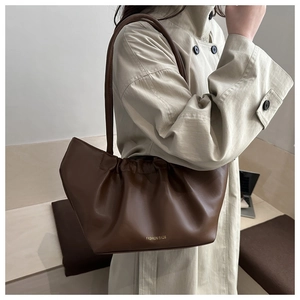 Detail of a brown pleated cloud bag with golden Fashion Bags text on beige trench coat