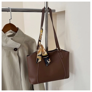 Detail of dark brown tote bag featuring contrast stitching and a silk scarf handle wrap