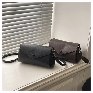 Detail view of minimalist crossbody bags in black and dark brown with a wrinkled texture