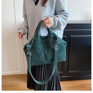 Detailed close-up of dark green corduroy tote bag featuring TOTE BAG embroidery text