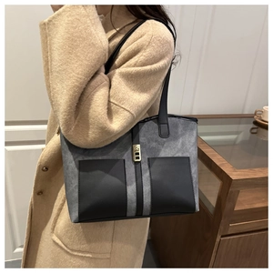 Close-up of color-block tote bag featuring gray matte texture and gold twist-lock detail