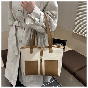 Detail view of large canvas and leather tote bag with vintage lock and contrast trim