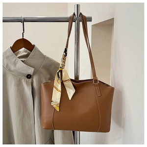 Detailed view of brown leather tote bag with elegant floral silk scarf and slim straps