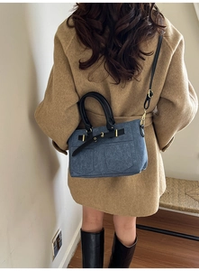 Detail of denim patchwork crossbody bag with black leather straps and gold hardware