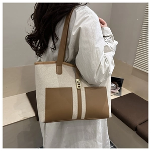 Detail of vintage canvas tote with brown leather patchwork and golden lock decoration