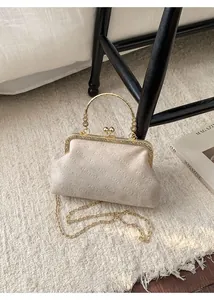 Detail of rich rabbit monogram shell bag with gold clasp and vintage ring handle