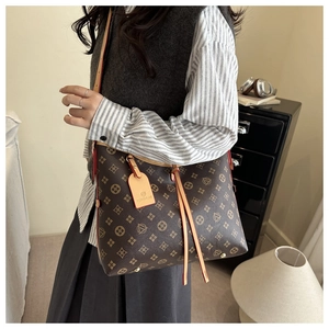 Close-up of brown monogram bucket bag with drawstring detail and branded leather tag