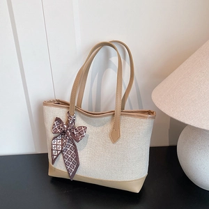 Large beige canvas tote bag with brown leather trim and elegant printed silk scarf handle