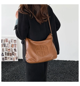 Brown leather tote bag showing large capacity and soft texture on a fashion model
