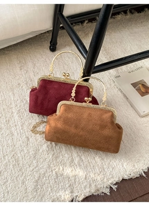 Close-up of velvet shell bag with gold clasp, metal chain, and rich rabbit pattern