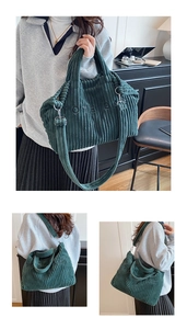 Detail of dark green corduroy tote bag showing embroidered text and shoulder strap