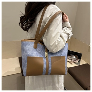Close-up of vintage large capacity tote bag featuring blue fabric and brown leather pockets