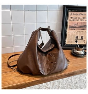 Detail of dark brown vintage faux leather tote bag with large embossed B logo and handle
