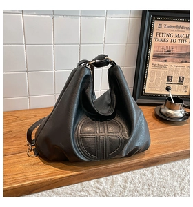 Detail of black leather hobo bag featuring embossed circular logo and gold hardware