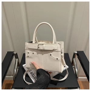 Detail of cream white leather handbag with silver buckle and denim pocket style stitching