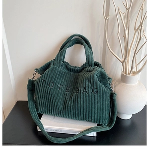 Close-up of deep green corduroy tote bag with embroidered logo and matching strap