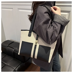 Detail of canvas tote bag with contrast black pockets and golden metal swivel lock