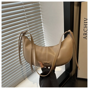 Detail of soft dumpling bag featuring minimalist metal buckle and long leather tassels