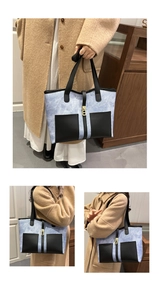 Detail view of large blue contrast tote bag with black pockets and gold buckle