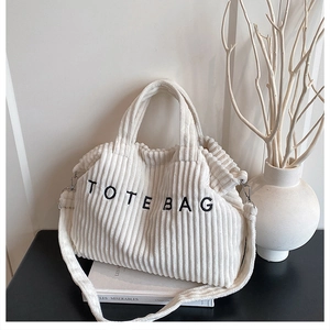 Detailed texture of off-white corduroy tote bag with embroidered TOTE BAG lettering