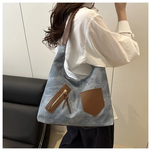 Detail of blue denim hobo bag with brown leather strap and side zipper pocket