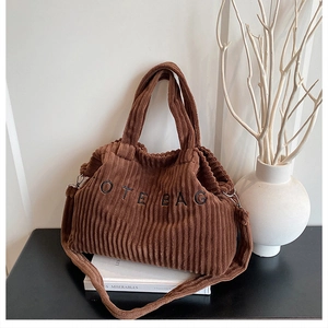 Close-up of brown corduroy tote bag featuring vertical texture and embroidered lettering