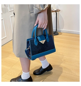 Detail of blue and black snakeskin pattern handbag with gold V-shaped metal buckle lock