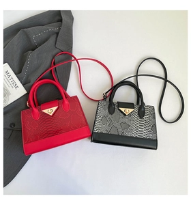 Detailed view of red and grey snakeskin texture handbags with gold V-shaped metal locks