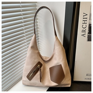 Detail of minimalist beige suede tote bag with brown leather handles and side zip pocket